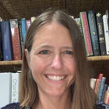 Kimberly Martin, smiling, in front of a bookshelf