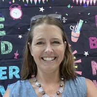 Kimberly Martin smiling in front of a classroom bulletin board